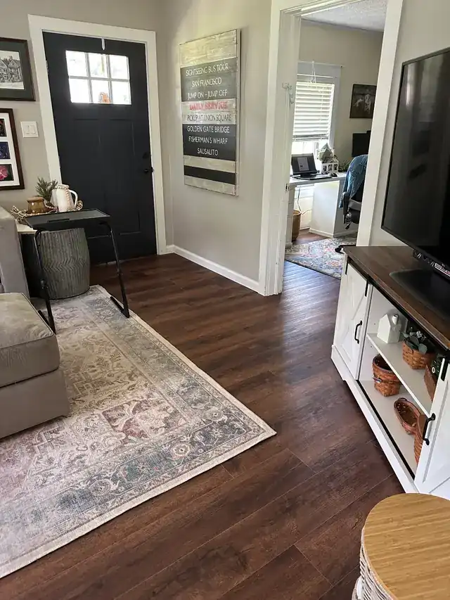 Dark vinyl plank floor running through a living room toward a home office